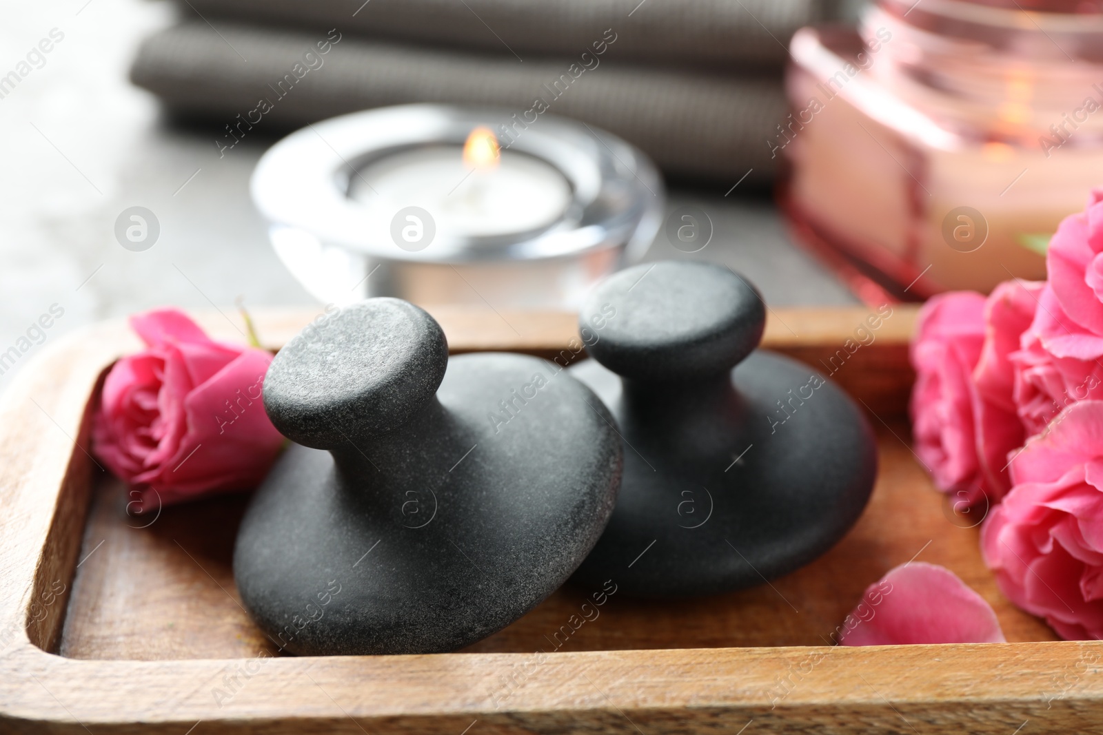 Photo of Spa stones, rose flowers and candles on table, closeup