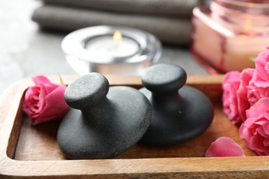 Spa stones, rose flowers and candles on table, closeup