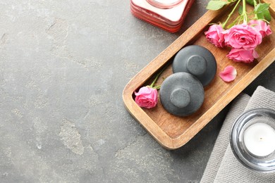 Photo of Spa stones, rose flowers and candles on grey table, flat lay. Space for text