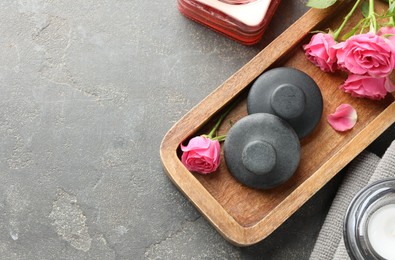 Photo of Spa stones, rose flowers and candles on grey table, flat lay. Space for text