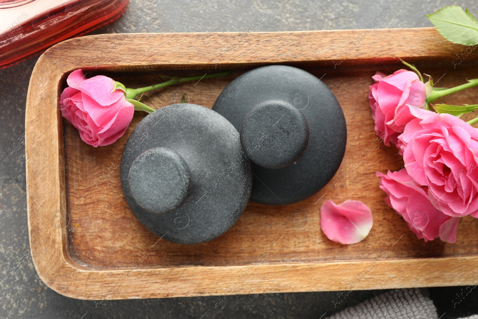 Photo of Spa stones and rose flowers on grey table, top view