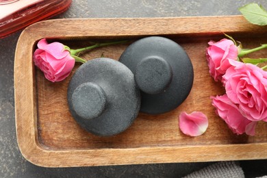 Photo of Spa stones and rose flowers on grey table, top view