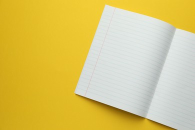 Photo of Open copybook on yellow background, top view. Space for text