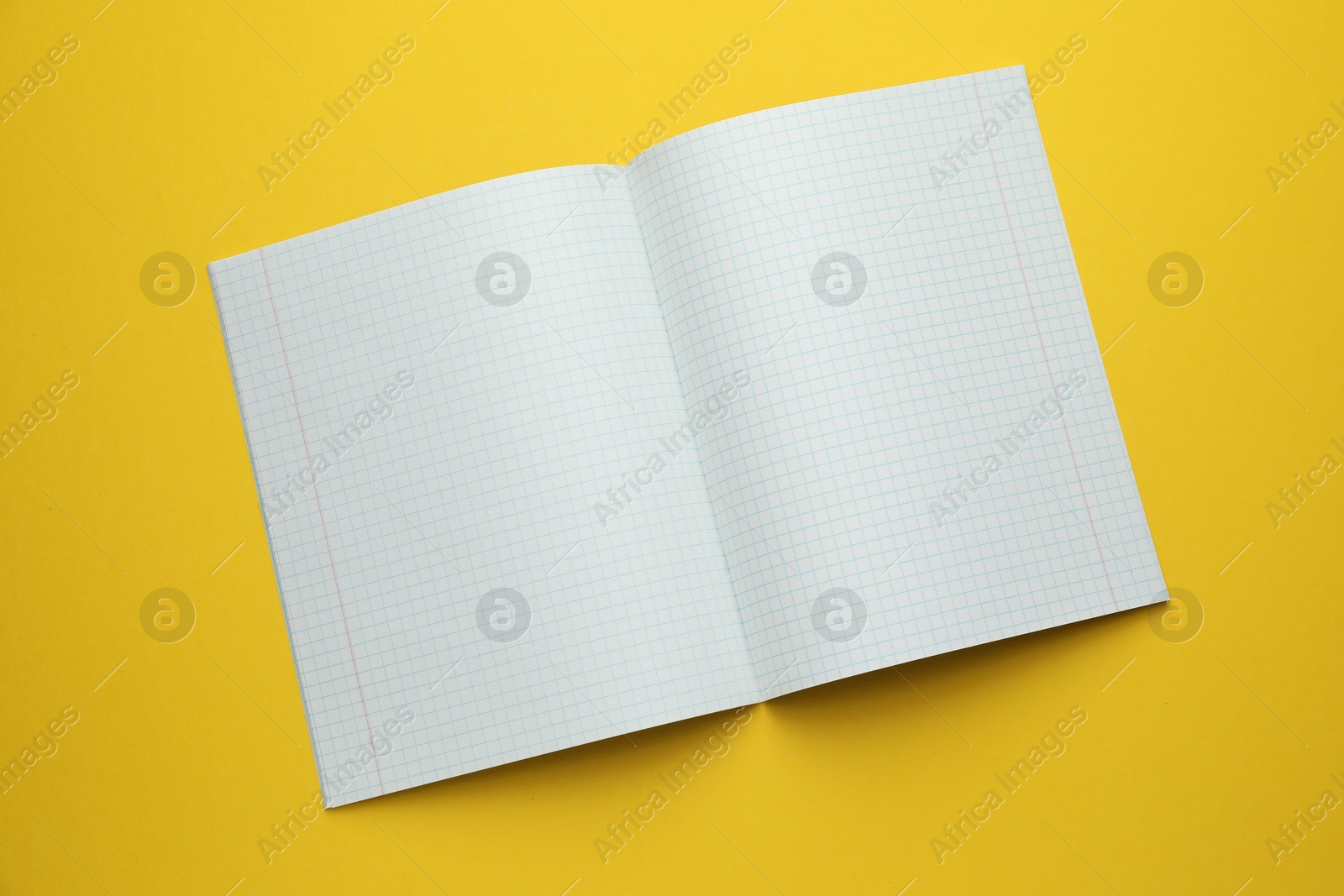 Photo of Open copybook on yellow background, top view