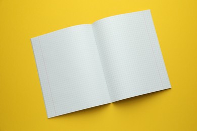 Photo of Open copybook on yellow background, top view