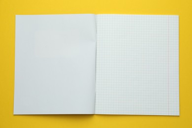 Photo of Open copybook on yellow background, top view