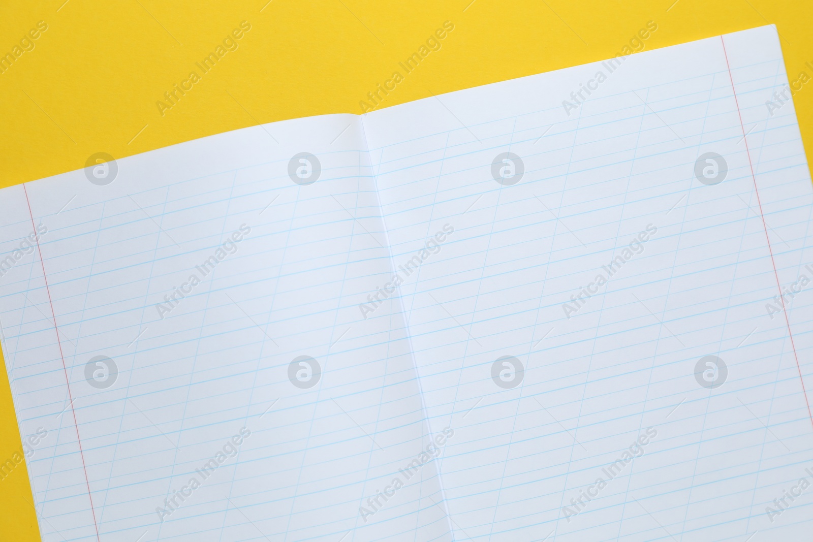 Photo of Open copybook on yellow background, top view