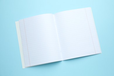 Photo of Open copybook on light blue background, top view