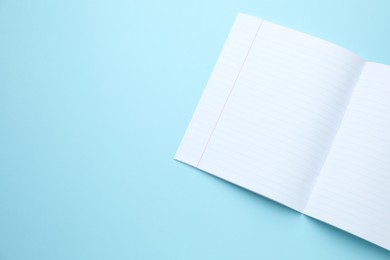 Photo of Open copybook on light blue background, top view. Space for text