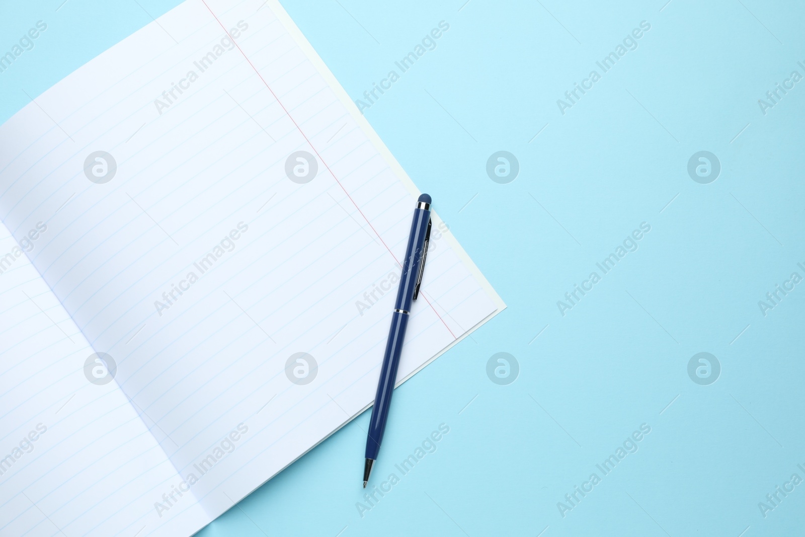 Photo of Open copybook and pen on light blue background, top view. Space for text