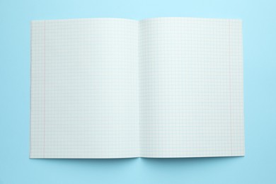 Photo of Open copybook on light blue background, top view