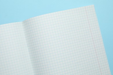 Photo of Open copybook on light blue background, top view