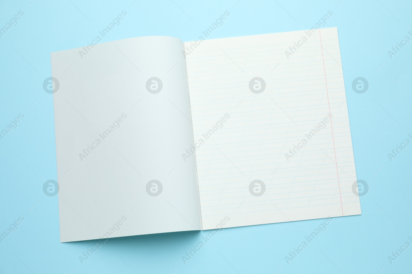 Photo of Open copybook on light blue background, top view