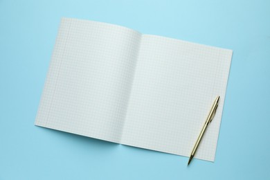 Photo of Open copybook and pen on light blue background, top view