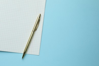 Photo of Open copybook and pen on light blue background, top view. Space for text