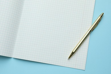 Photo of Open copybook and pen on light blue background, top view