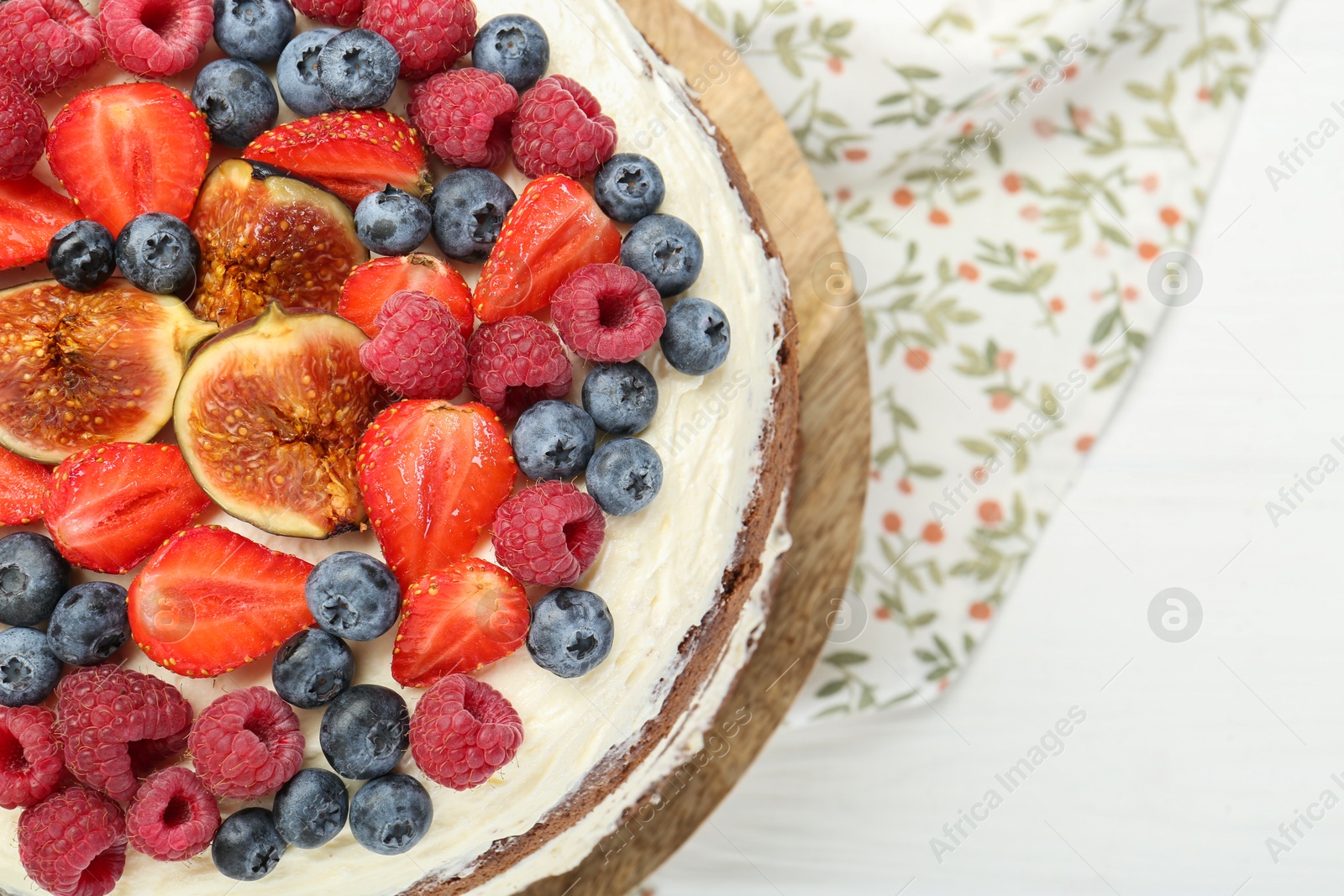 Photo of Delicious chocolate sponge cake with berries on white wooden table, top view