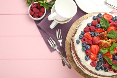 Delicious chocolate sponge cake with berries served on pink wooden table, top view. Space for text