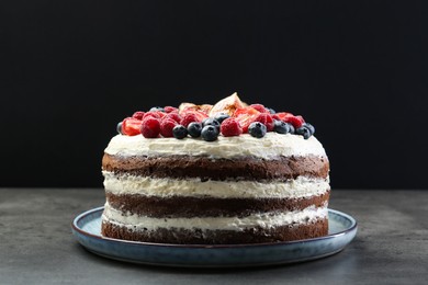 Photo of Delicious chocolate sponge cake with berries on grey table