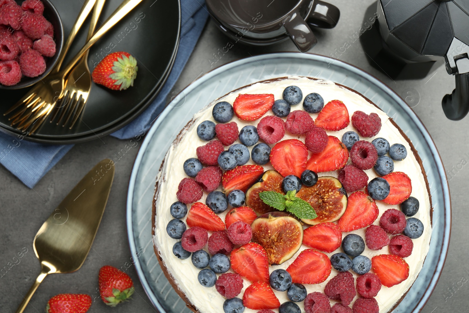 Photo of Delicious chocolate sponge cake with berries served on grey table, top view