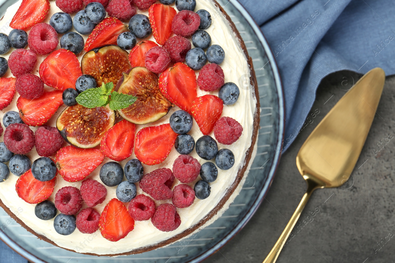 Photo of Delicious chocolate sponge cake with berries and server on grey table, top view