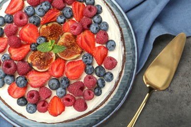 Delicious chocolate sponge cake with berries and server on grey table, top view