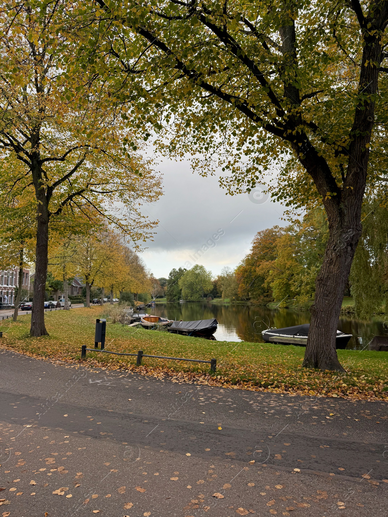 Photo of Beautiful view of canal with moored boats and colorful fallen leaves on autumn day