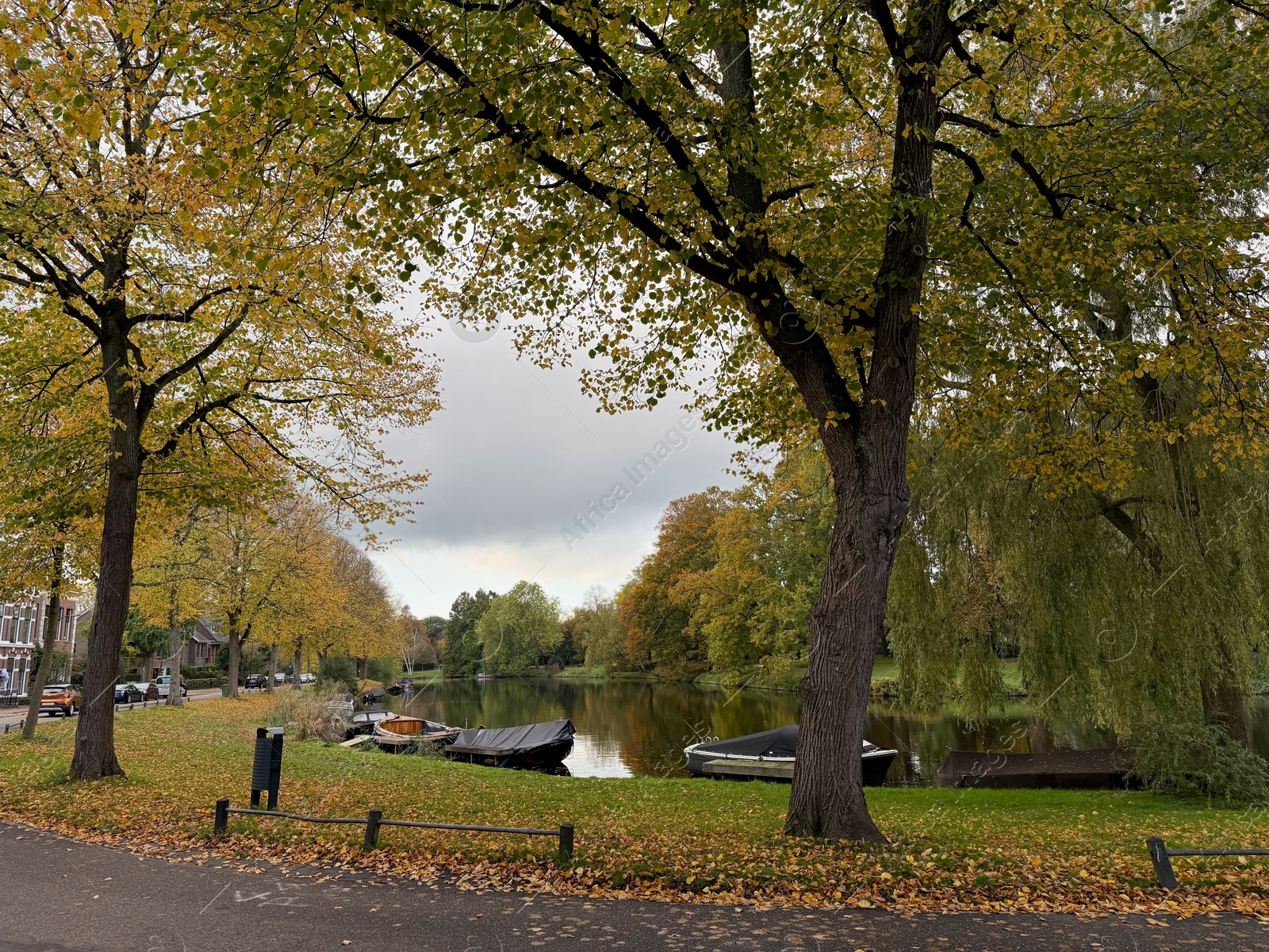 Photo of Beautiful view of canal with moored boats and colorful fallen leaves on autumn day