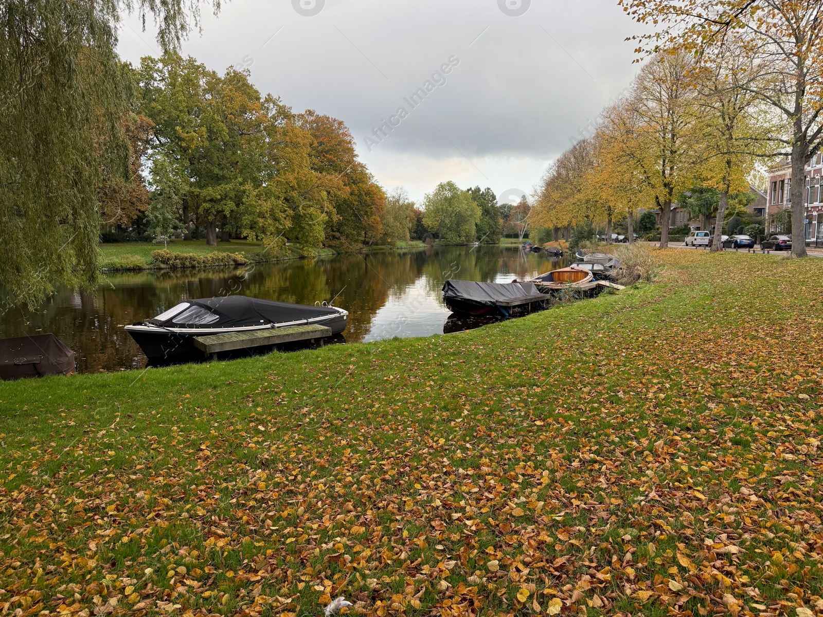 Photo of Beautiful view of canal with moored boats and colorful fallen leaves on autumn day