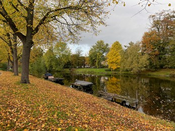 Photo of Beautiful view of canal with moored boats and colorful fallen leaves on autumn day