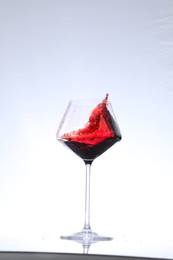 Photo of Red wine splashing in glass on white background