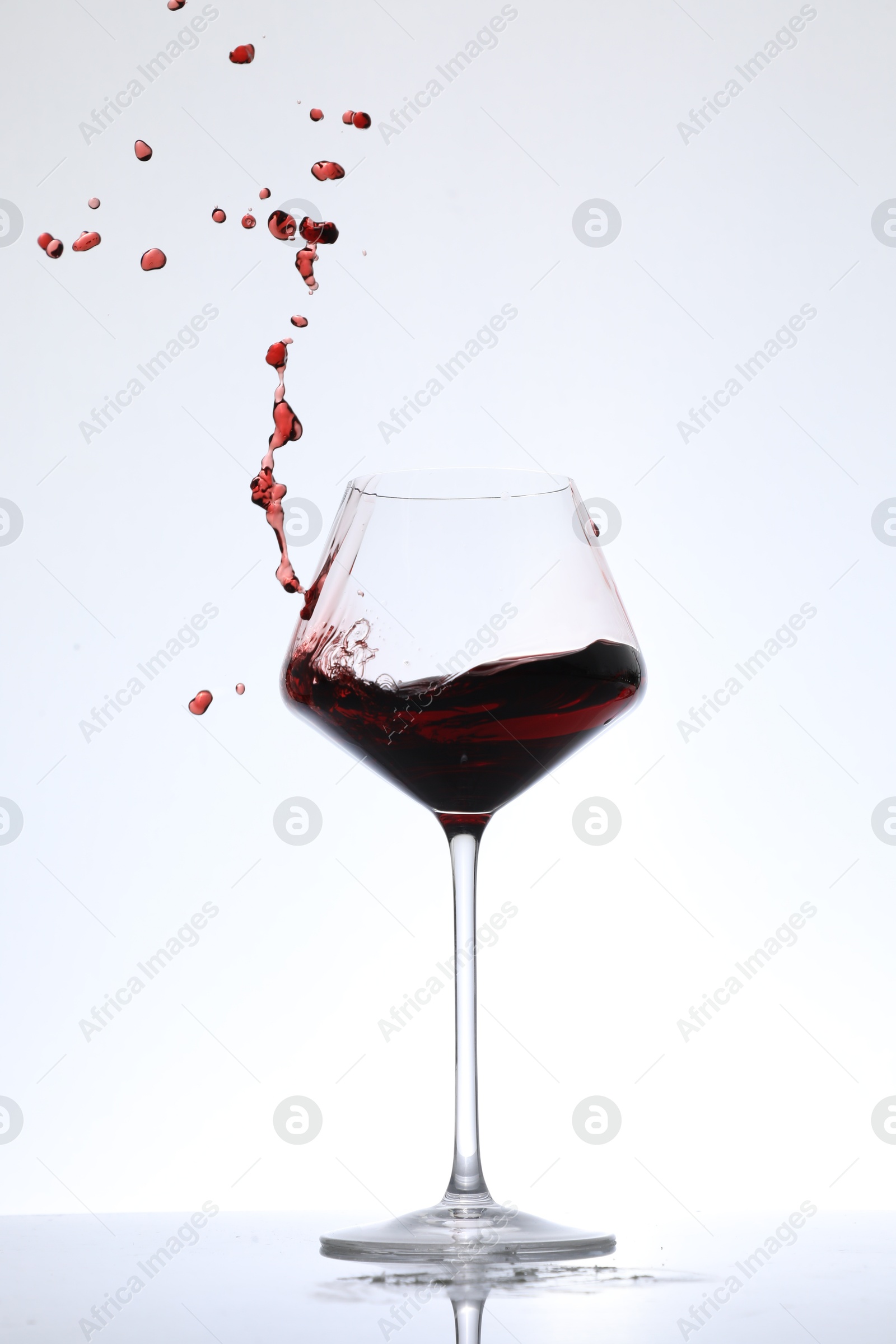 Photo of Red wine splashing in glass on white background