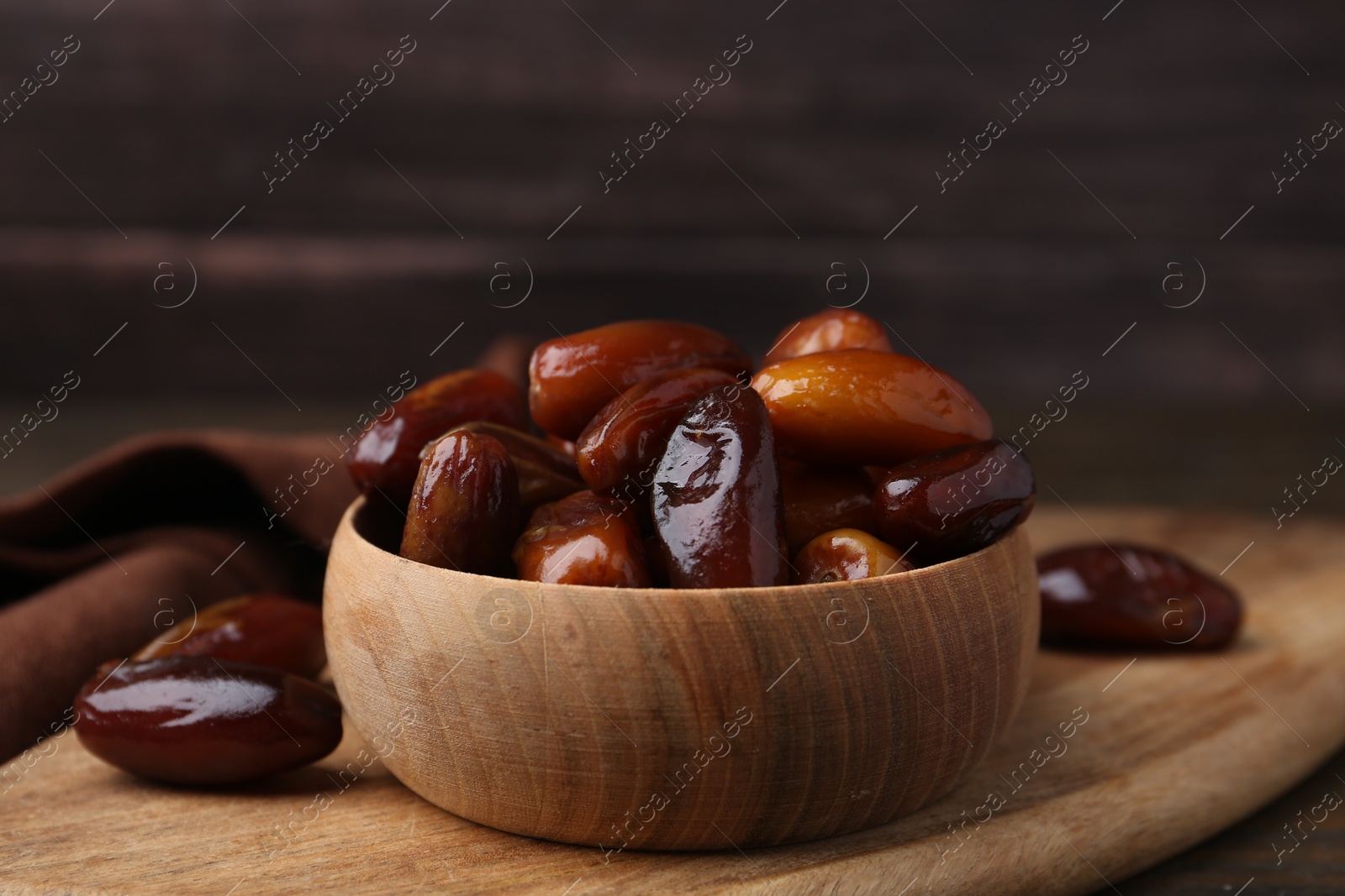 Photo of Tasty sweet dried dates in bowl on wooden table, closeup