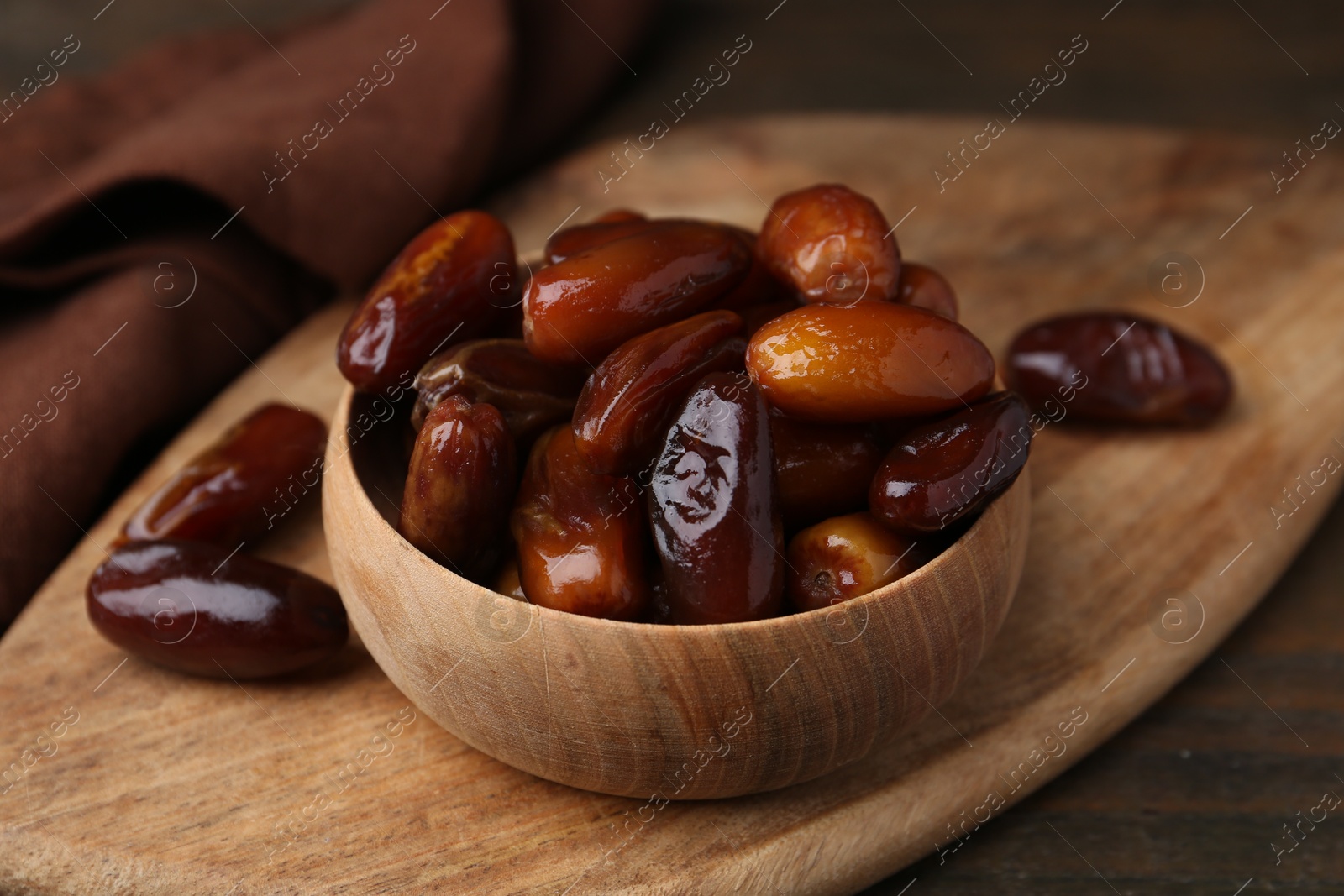 Photo of Tasty sweet dried dates in bowl on wooden table, closeup