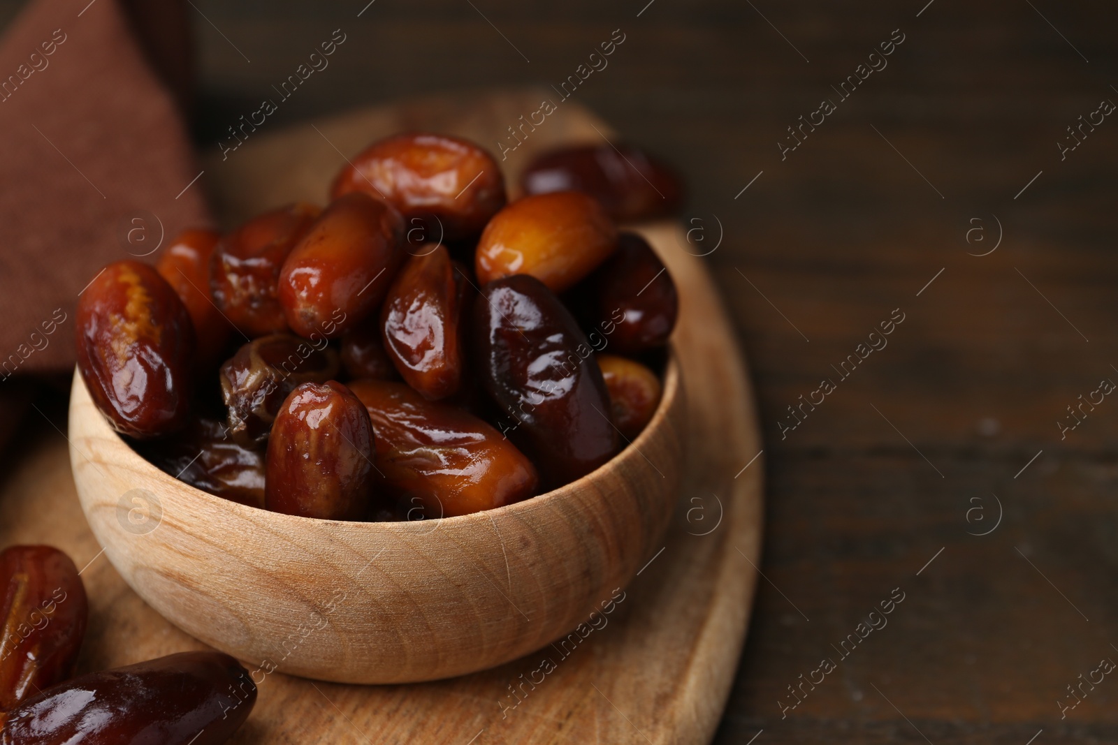 Photo of Tasty sweet dried dates in bowl on wooden table, closeup. Space for text