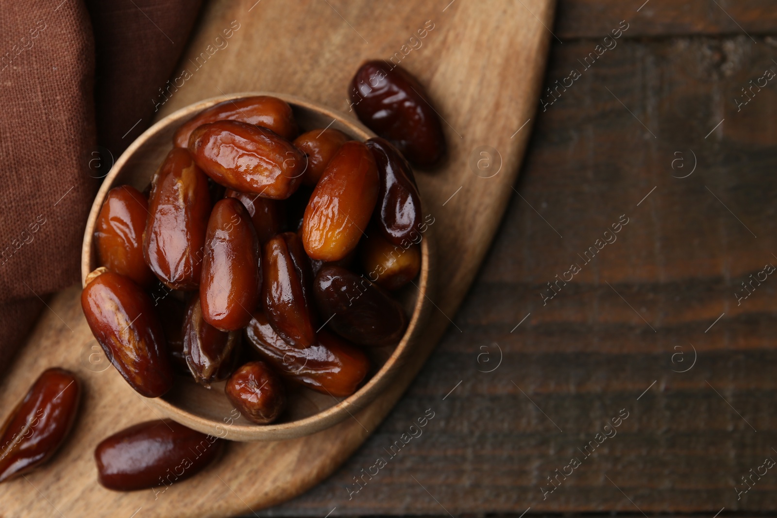 Photo of Tasty sweet dried dates in bowl on wooden table, top view. Space for text