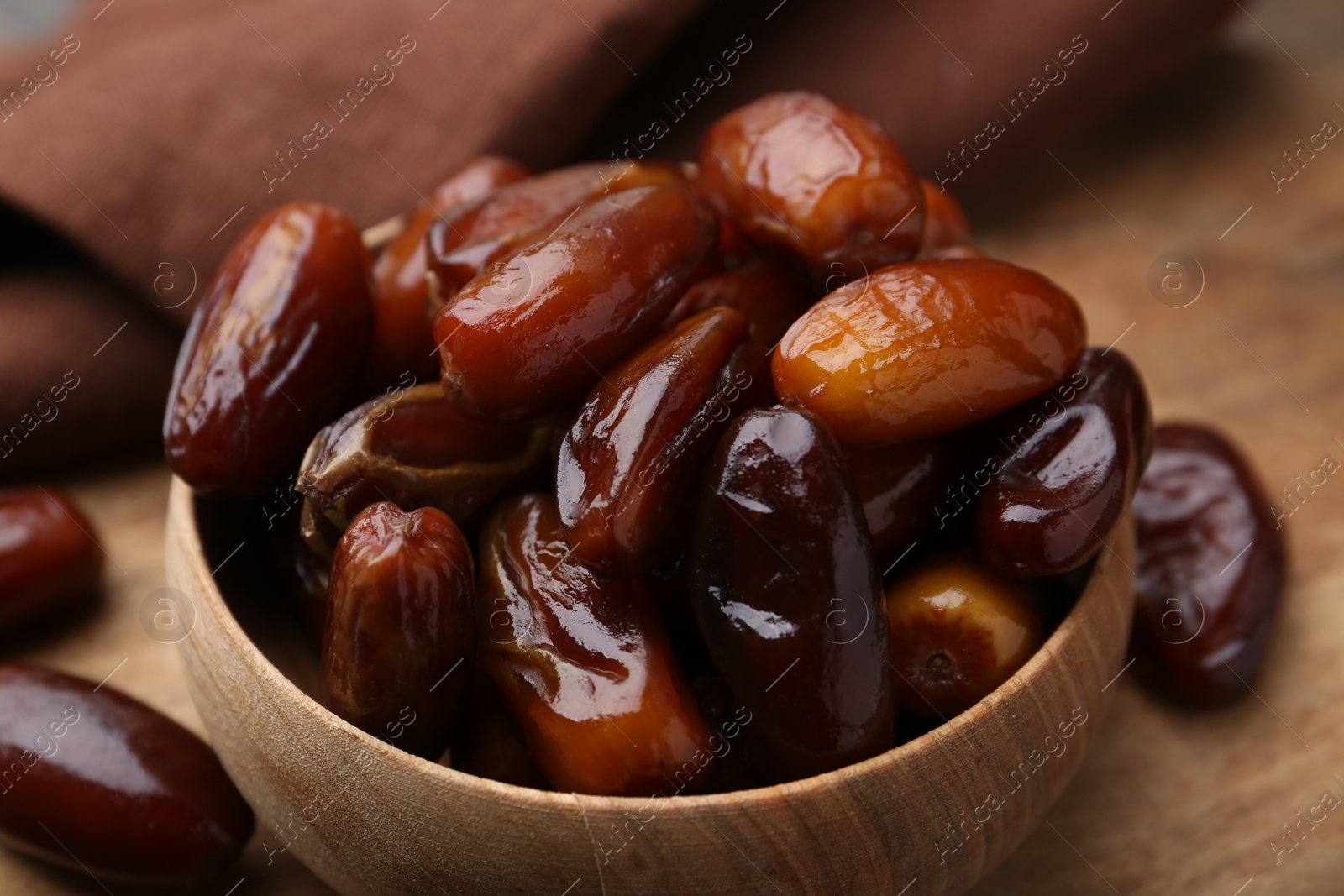 Photo of Tasty sweet dried dates in bowl on wooden table, closeup