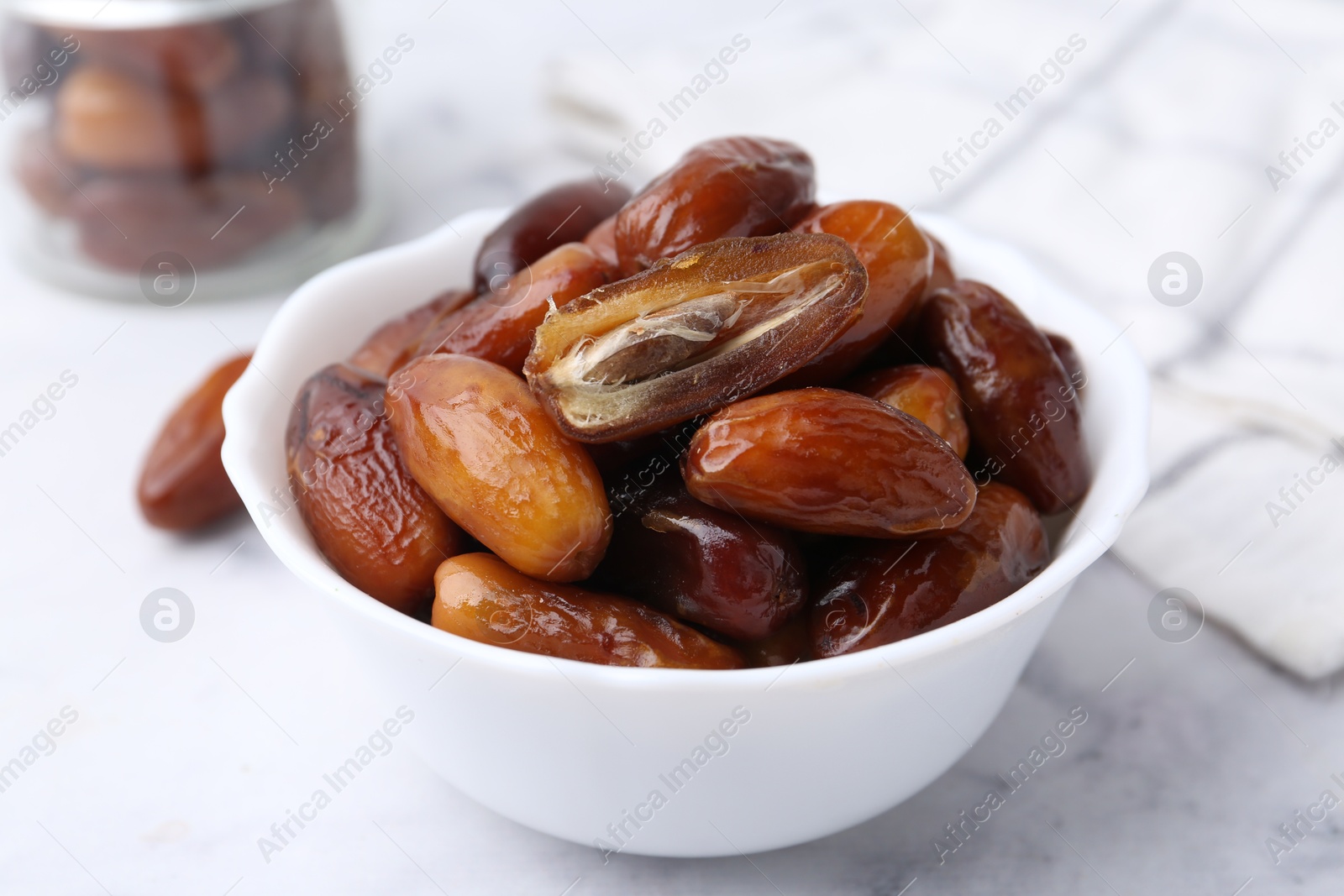 Photo of Tasty dried dates in bowl on white marble table, closeup