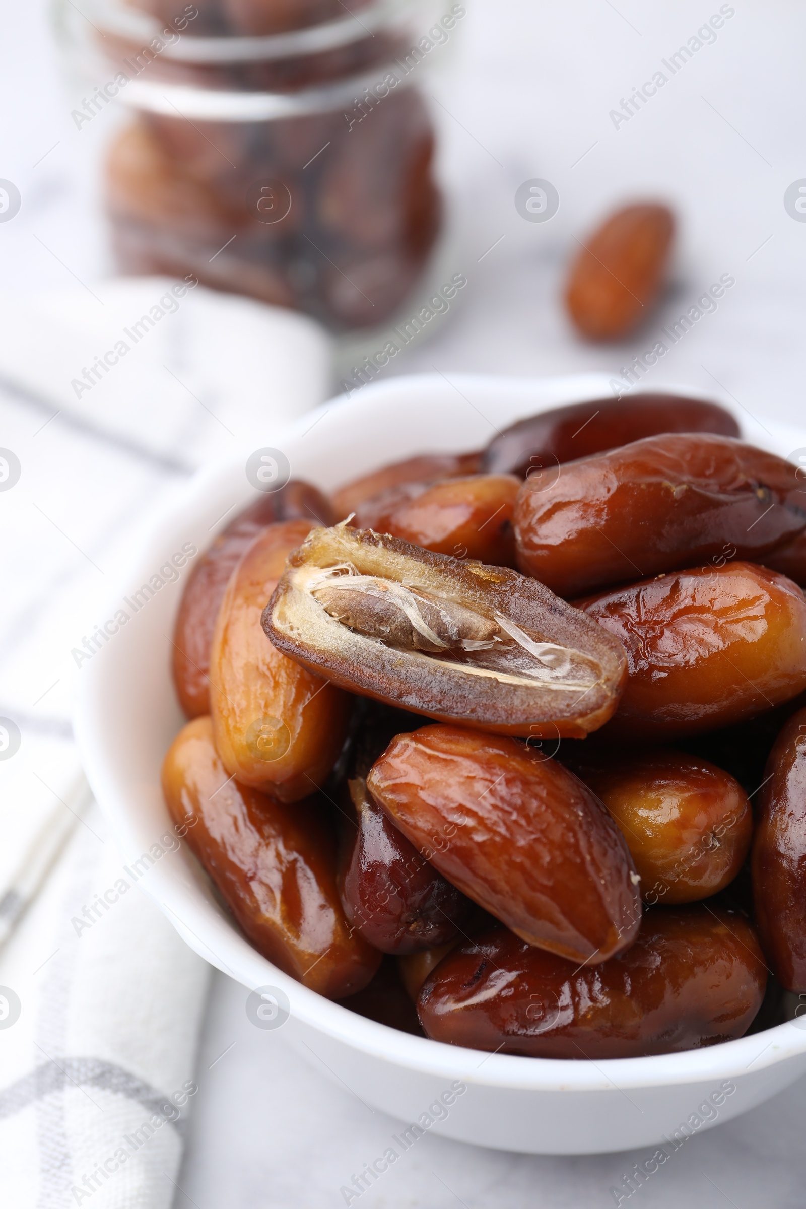 Photo of Tasty sweet dried dates in bowl on white table, closeup