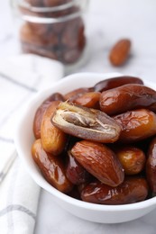 Photo of Tasty sweet dried dates in bowl on white table, closeup