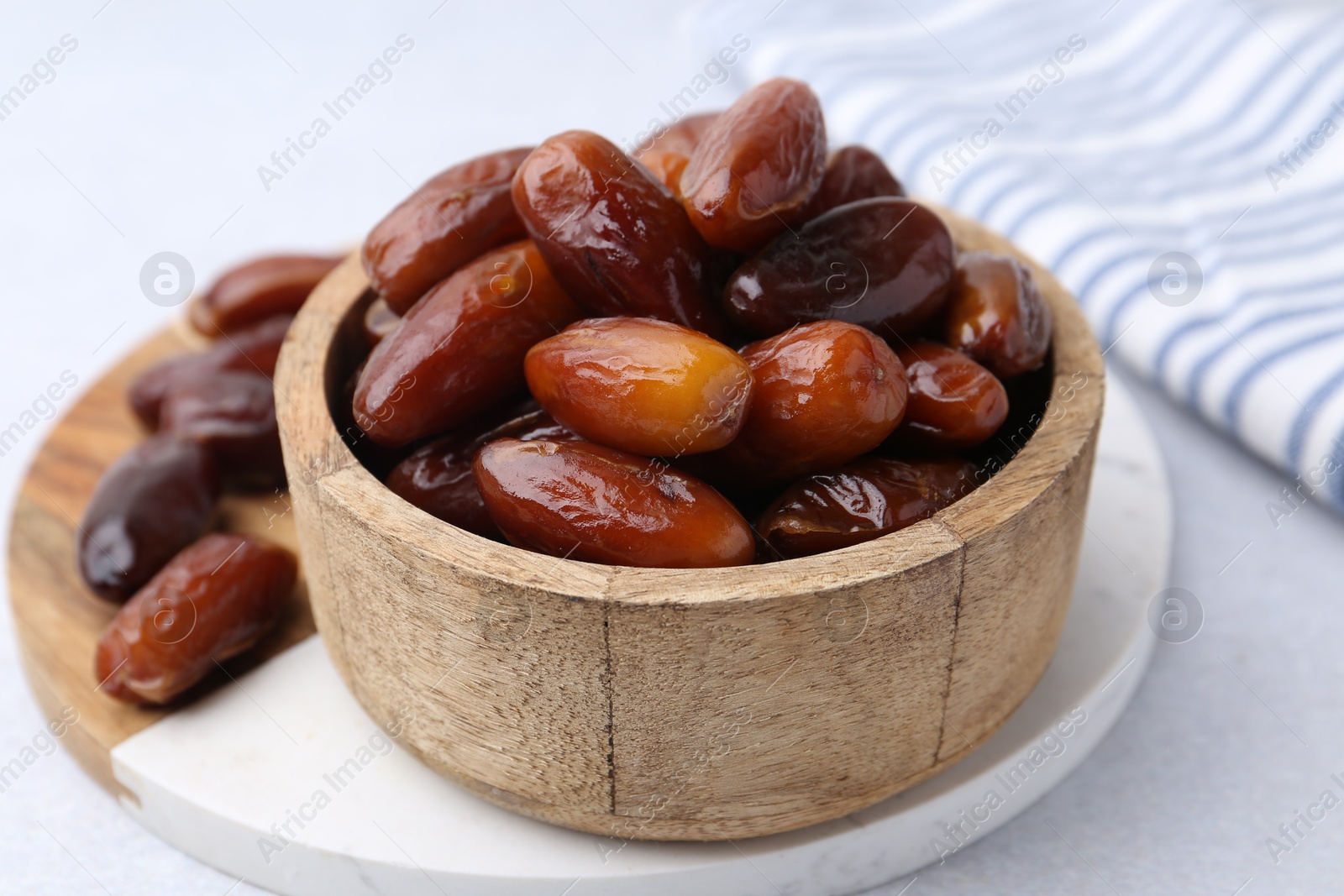 Photo of Tasty dried dates in wooden bowl on white table, closeup