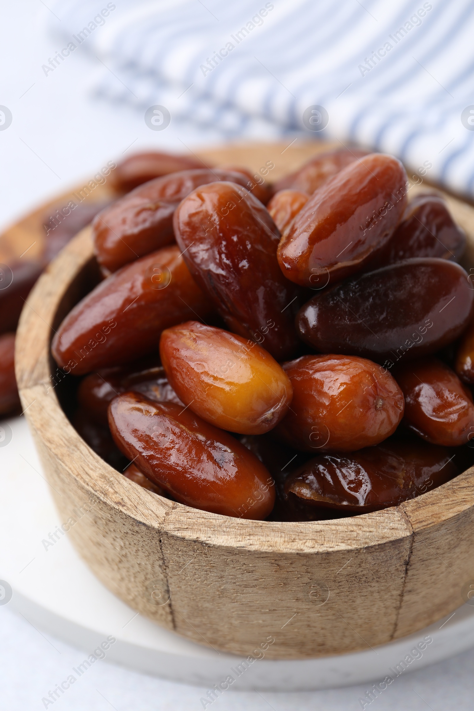 Photo of Tasty dried dates in wooden bowl on white table, closeup