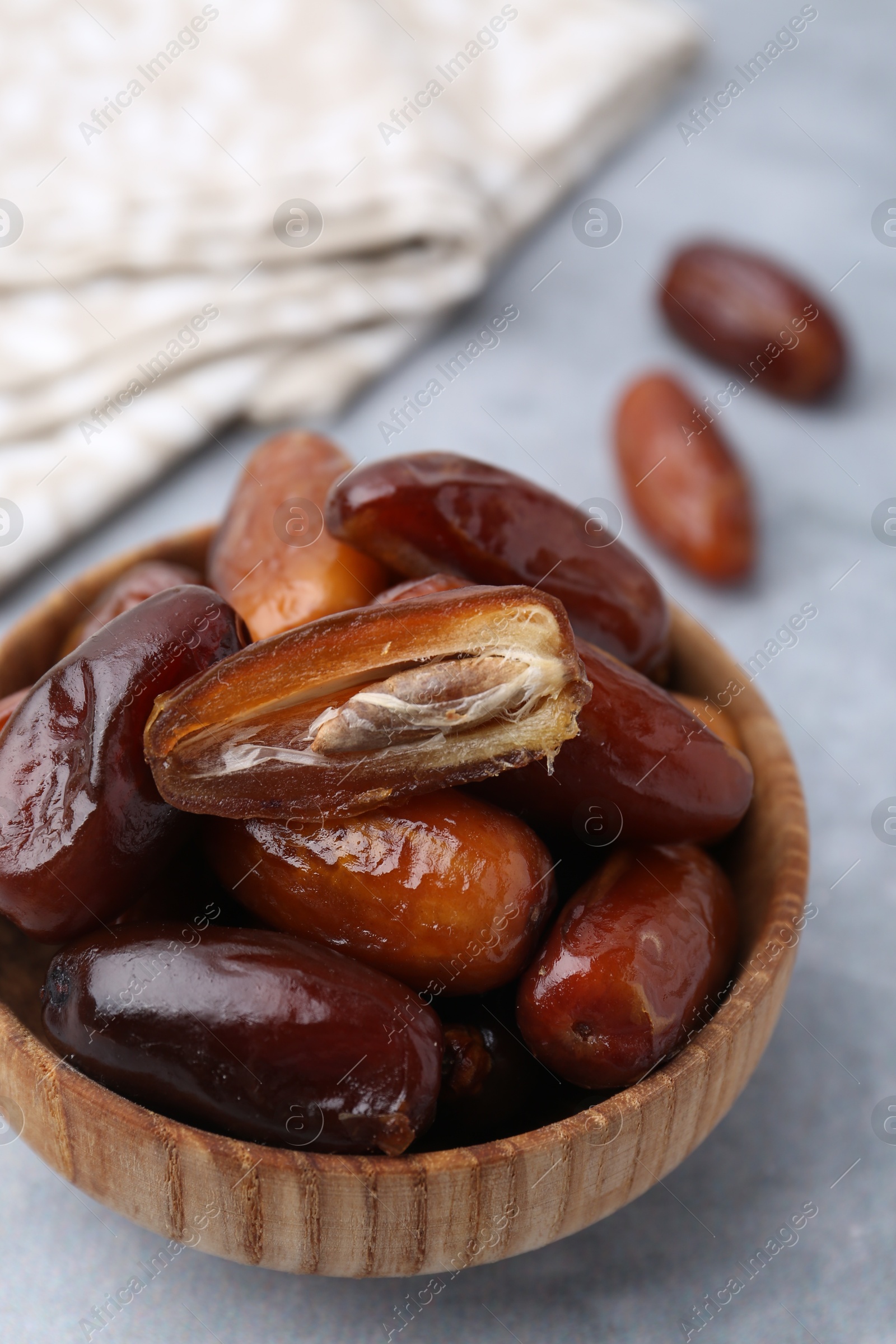 Photo of Tasty dried dates in bowl on light grey table, closeup