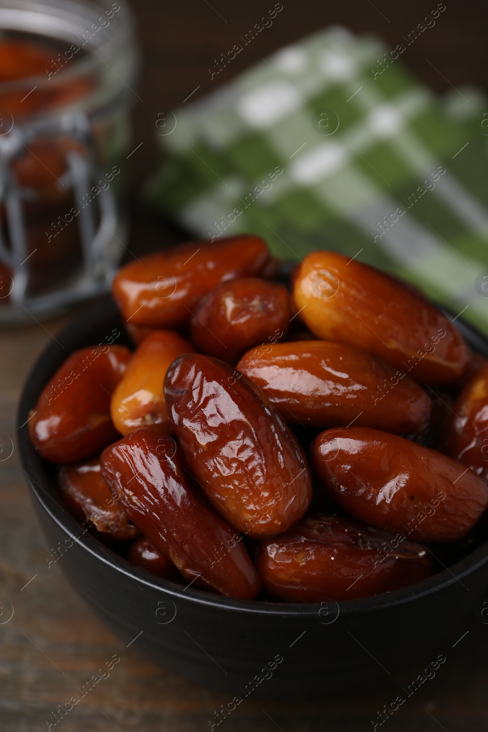 Photo of Tasty dried dates in bowl on wooden table, closeup