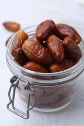 Photo of Tasty dried dates in jar on white table, closeup