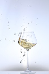 Photo of Tasty wine splashing in glass on white background