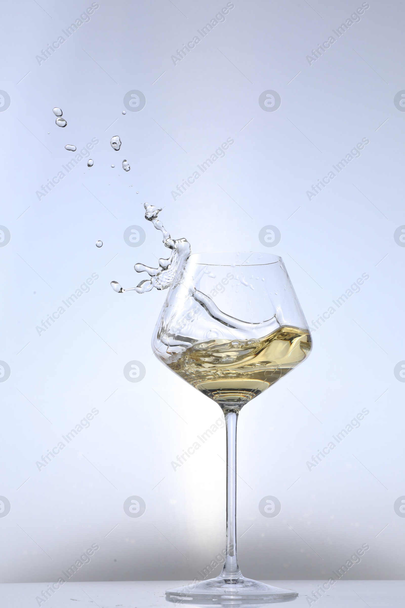 Photo of Tasty wine splashing in glass on white background