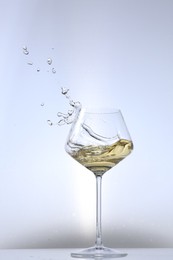 Photo of Tasty wine splashing in glass on white background