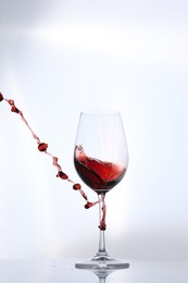 Photo of Red wine splashing in glass on white background