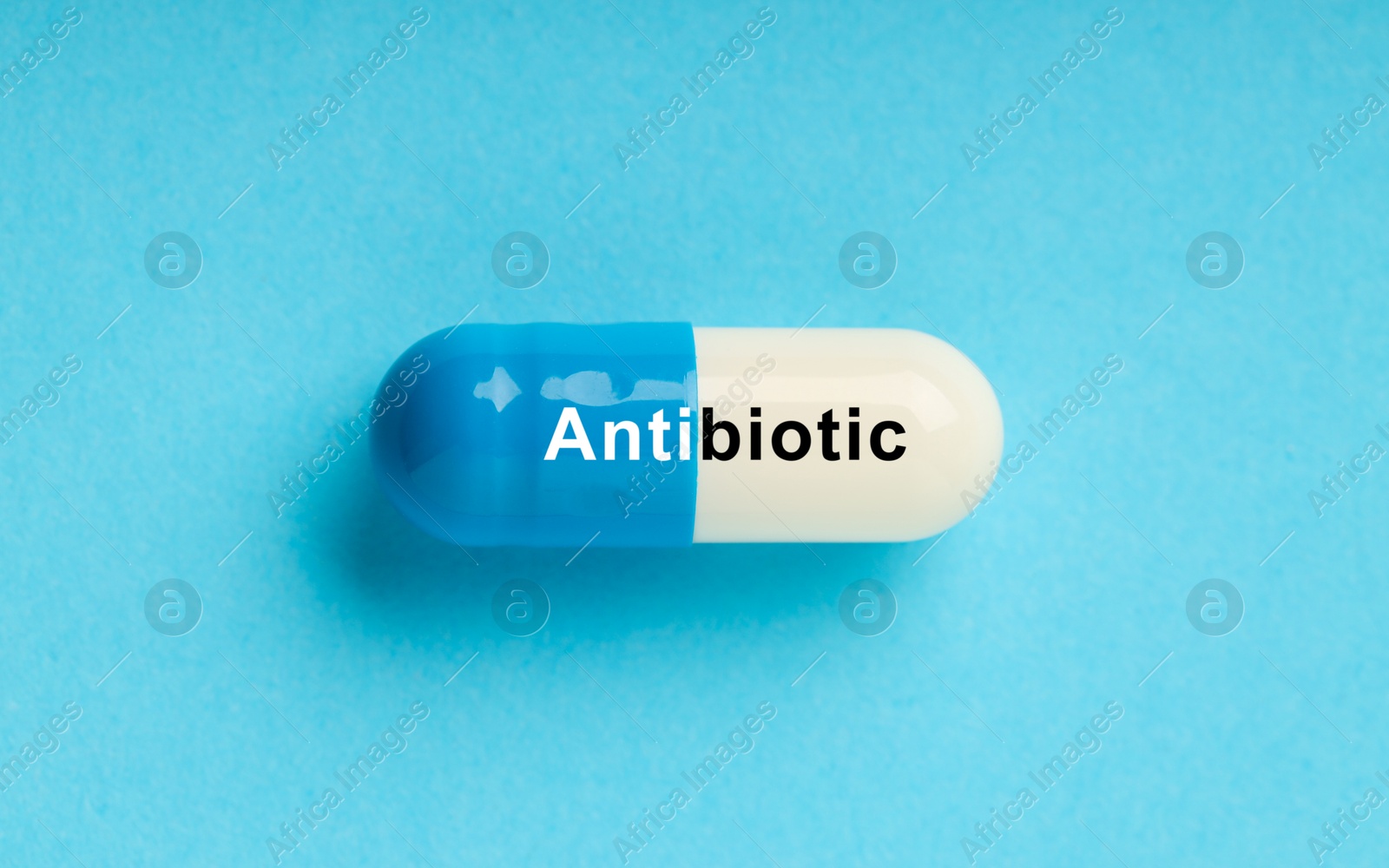 Image of Capsule with word Antibiotic on light blue background, top view